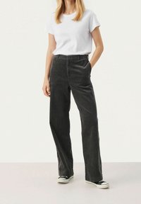 Mustat corduroy-housut suoranlahkeisella siluetilla, joissa on sivutaskut ja vyötärö. Yhdistetty yksinkertaiseen valkoiseen t-paitaan ja lenkkareihin.