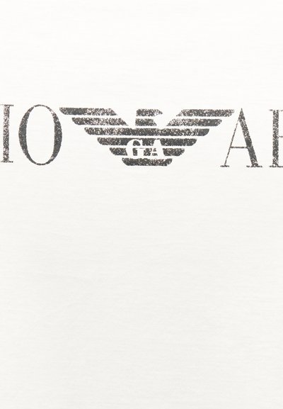 Μαύρο στυλιζαρισμένο λογότυπο αετού με τα γράμματα "GA" στο εσωτερικό, τοποθετημένο στο κέντρο μεταξύ μερικώς ορατών μαύρων γραμμάτων σε λευκό φόντο.