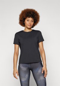 Black short-sleeve athletic t-shirt with a round neckline, made from a smooth, lightweight fabric, paired with patterned blue and black leggings.