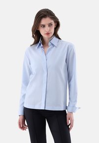 Camicia azzurro chiaro a maniche lunghe in tessuto morbido con colletto button-down, caratterizzata da una fodera interna del colletto grigia e un orlo dritto.