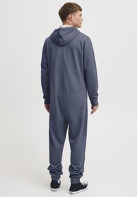 Navy blue hooded onesie made of soft fabric, featuring a back pocket and cuffed sleeves and ankles for a snug fit.