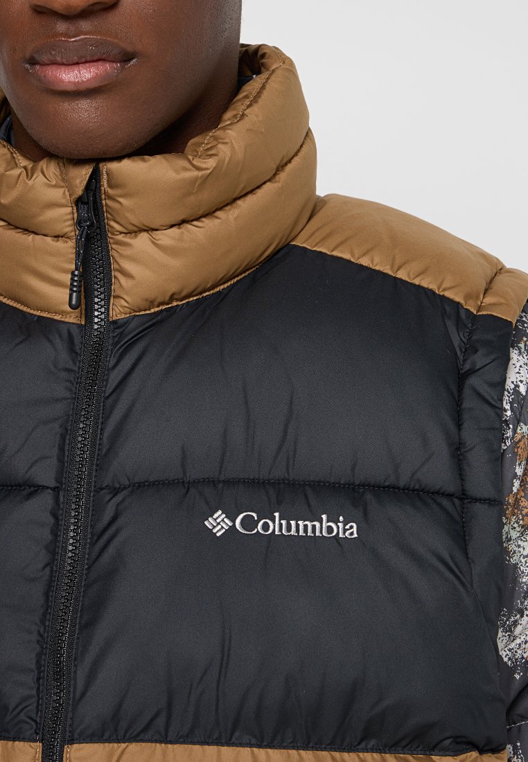 Kamizelka puchowa z czarnym korpusem, brązowym kołnierzem i wzorzystymi bocznymi panelami. Grawerowane logo Columbia na piersi. Zamek błyskawiczny z przodu.