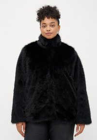 Crni faux fur kaput s visokim ovratnikom, koji ima mekan, teksturiran završetak i opušteni kroj. Dugi rukavi i minimalistički dizajn.