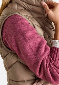 Weste mit Steppmuster in Braun und einem gestrickten, pinken Ärmelsaum, der ein strukturiertes Muster und gerippte Akzente aufweist.