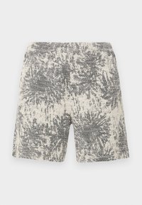Strikkede shorts i kremhvitt og svart med et teksturert, abstrakt mønster. Elastisk midjebånd gir komfort og enkelhet i bruk.