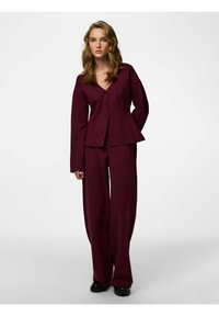 Krojen odijelo boje burgundca s jaknom na V-izrez s gumbima i hlačama širokih nogavica. Glatka tekstura sa strukturiranim krojem.