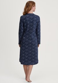 Abito blu navy a maniche lunghe con motivo a luna crescente bianca e scollo rotondo. Il tessuto sembra morbido e liscio, con una vestibilità comoda e lunghezza fino al polpaccio.