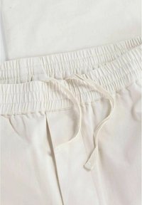 Ljust beige bomullsshorts med ett elastiskt midjeband, dragsko och subtila veckdetaljer fram.