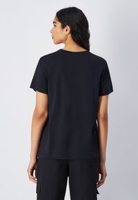 Sort kortærmet T-shirt lavet af blødt bomuld, med rund halsudskæring og en løs pasform, med minimale sømme og ingen synlige logoer.