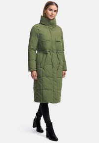 Abrigo acolchado verde oliva con cuello alto, cintura ceñida con cinturón, dos bolsillos delanteros y detalles de botones en el dobladillo. Textura de tela suave.