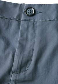 I pantaloni di cotone grigi presentano una consistenza liscia, una tasca frontale e un dettaglio con bottone nero in vita con cuciture a contrasto.