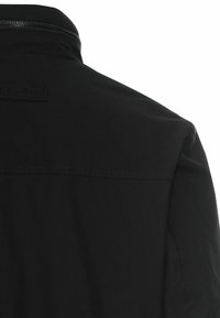 Black jacket featuring a smooth, matte texture, high collar, and a zip closure at the back. Minimalistic design with no visible hardware.