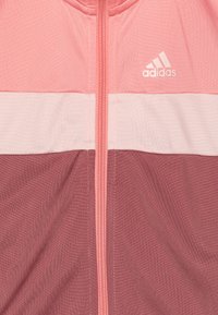 Chaqueta ligera de Adidas en rosa y malva, con cierre frontal, bloques de color horizontales en contraste y un pequeño logo en el pecho.