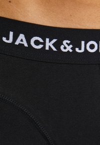 Schwarze Unterwäsche mit einem weichen, elastischen Bund, der mit weißen "JACK & JONES"-Buchstaben versehen ist. Glattes Material mit einer figurbetonten Passform.