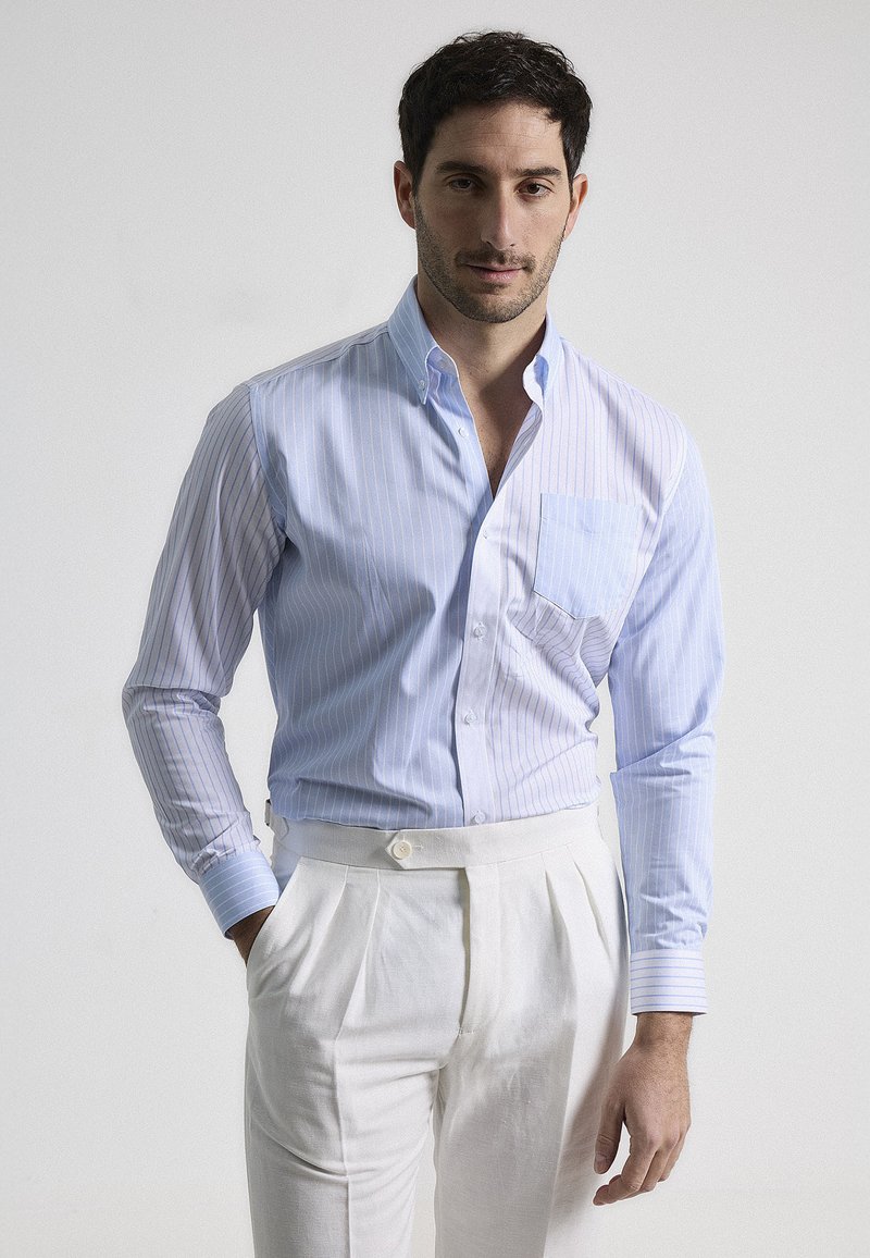 Camisa abotonada de rayas azul claro con un bolsillo, corte ajustado, combinada con pantalones blancos con pliegues. Tejido de algodón suave, de mangas largas.