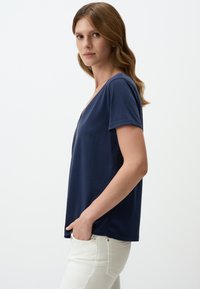 Dunkelblaues Kurzarm-T-Shirt mit V-Ausschnitt, lockere Passform und weicher Stoff, kombiniert mit hellen Jeans.