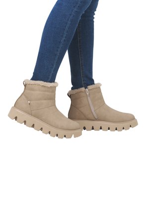 Bottines beiges avec une doublure en fourrure douce, dotées d'une fermeture éclair sur le côté et d'une semelle en caoutchouc épaisse et striée. Surface texturée et design rembourré.