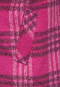 Tela de cuadros rosa con un acabado suave y texturizado. El patrón presenta franjas más oscuras sobre un fondo rosa más claro, incluyendo un detalle de bolsillo.