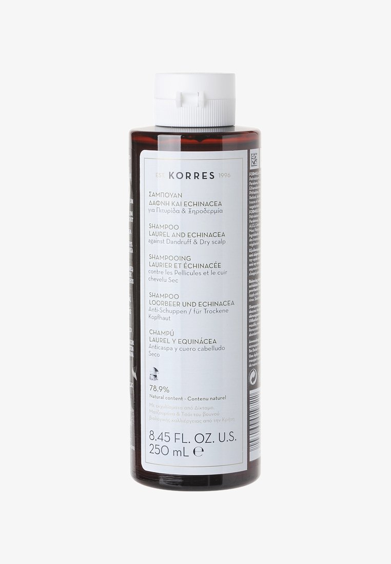 Brown plastic bottle of shampoo with white screw cap. Label features text in multiple languages and lists ingredients and usage instructions.