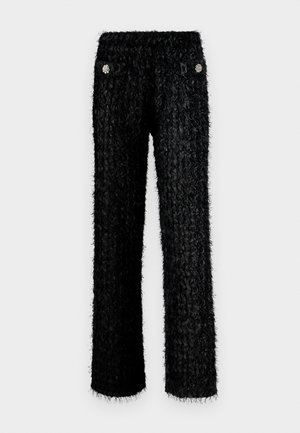 Pantalons noirs en peluche avec un design texturé, dotés d'une taille haute et de deux poches avant ornées de décorations florales rondes.