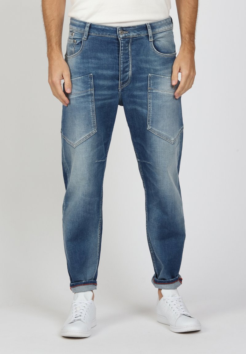 Blaue Jeans aus Denim mit einer hellen Waschung, mit schrägen Fronttaschen und hochgekrempelten Säumen, kombiniert mit weißen Sneakern.