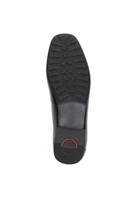 Schwarze Schuhsohle mit einer strukturierten Gummioberfläche und Traktionsmustern, einem auffälligen Markenlogo und einem runden roten Akzent in der Nähe der Ferse.