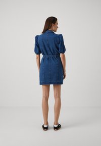 Jeansklänning med puffärmar, midjebälte och kort längd. Djupblå färg, slät textur och minimalistisk design.