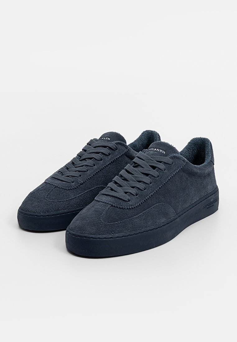 Donkerblauwe suede sneakers met een lage bovenkant, een gestructureerde bovenkant, een ronde neus en een platte rubberen zool; voorzien van opvallende stiksels en vetersluiting.