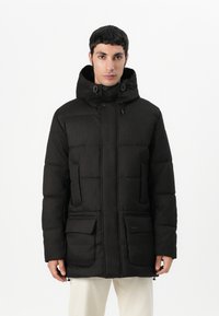 Veste rembourrée noire avec un col montant et une capuche ajustable, dotée de deux poches avant et d'un design élégant et texturé.