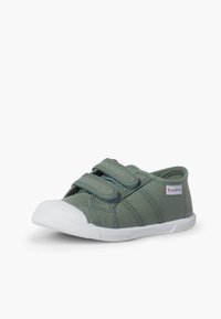 Scarpa verde in tela con due cinturini in velcro, punta in gomma bianca e lati texture. Suola piatta bianca con un leggero motivo di battistrada.