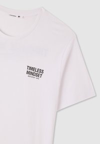 Biała bawełniana koszulka z napisem „TIMELESS MINDSET BED-STUY - NYC” w pogrubionej czarnej czcionce po lewej stronie na górze. Krótkie rękawy, klasyczny okrągły dekolt.