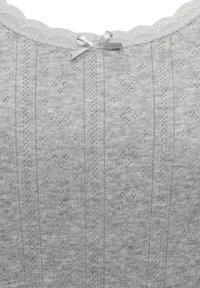 Hellgrau gemusterte Bluse mit gewelltem Ausschnitt, die ein kleines silbernes Banddetail aufweist. Hergestellt aus einem strukturierten Strickstoff mit vertikalen Streifen.