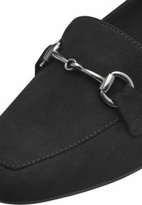Mocasin de ante negro con punta redondeada, acento de hardware plateado y costuras en contraste a lo largo de los bordes para un detalle adicional.