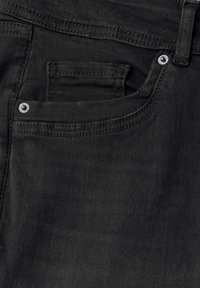 Tessuto di denim nero con una tasca frontale caratterizzata da un rivetto d'accento argentato. La texture è liscia con dettagli di cucitura visibili.