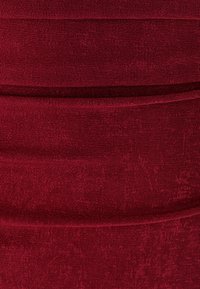 Červená rebrovaná tkanina s vertikálnymi líniami a hladkou textúrou. Detailný záber, zameraný na rovnomerný vzor a sýtu farbu.