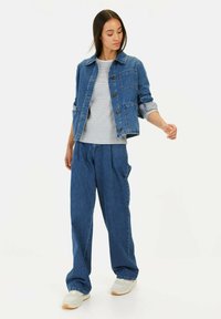 Jeansjacke mit Kragen, Knopfleiste und zwei Fronttaschen. Gekoppelt mit einem gestreiften Shirt und lässigen Jeanshosen.