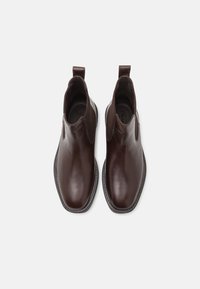 Botas de cuero marrón hasta el tobillo con paneles elásticos laterales, puntera afilada y suela contrastante. Textura suave con un diseño elegante.