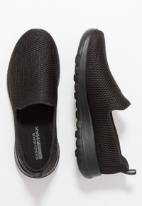 Sneakers neri senza lacci realizzati in mesh traspirante, con una tomaia testurizzata, suola flessibile e collo imbottito per il comfort.