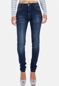Jeans skinny in denim blu scuro, con tasche standard, chiusura con bottone e leggera scoloritura sulla parte anteriore. Tessuto liscio con cuciture minime.