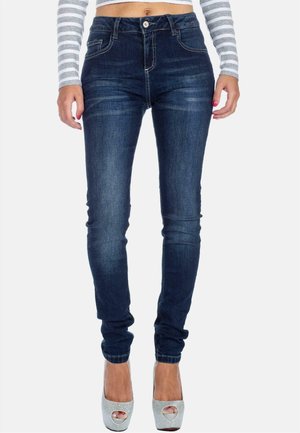 Jeans skinny en denim bleu foncé, avec poches standard, fermeture à bouton et légères décolorations à l'avant. Texture lisse avec un minimum de coutures.