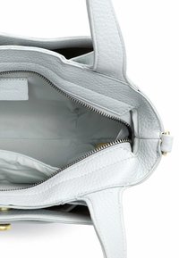 Světle šedá kožená kabelka s texturovaným povrchem, zapínáním na zip a dvěma otevřenými přihrádkami. Má zlaté kování a pevné popruhy.