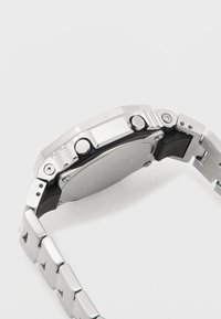 Metallkellaga käekell, roostevabast terasest korpus, musta kummist aktsentide ja poleeritud hõbedase randmeotstega. Omab kahte nupuvajutust ja siledat tagust.