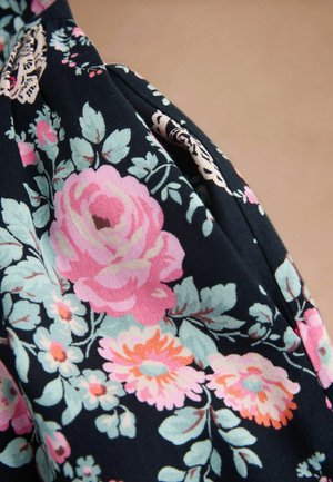 Mørkt stof med et blomsterprint bestående af store lyserøde, orange og lyseblå blomster samt grønne blade på en beige baggrund.