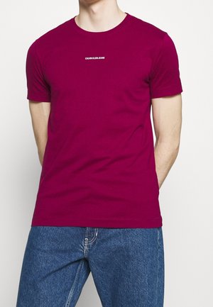 Strak gesneden t-shirt met korte mouwen in helder magenta katoen. Witte "CALVIN KLEIN JEANS" logo gecentreerd op de borst. Klassieke ronde hals.