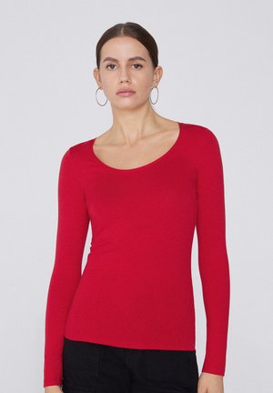 Haut rouge à manches longues avec un décolleté arrondi, fabriqué dans un tissu lisse et extensible. Design ajusté avec une légère courbe à l'ourlet.