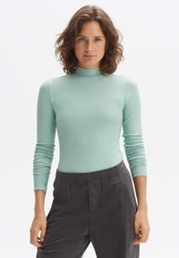 Mintgroene geribbelde coltrui met lange mouwen en een aansluitend ontwerp, gecombineerd met donkergrijze corduroy broek met een elastische tailleband.