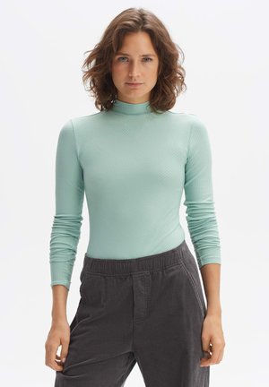 Mintgroene geribbelde coltrui met lange mouwen en een aansluitend ontwerp, gecombineerd met donkergrijze corduroy broek met een elastische tailleband.