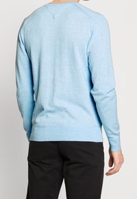 Hellblau farbener Langarm-Pullover aus weichem, strukturiertem Stoff mit gerippten Bündchen und Saum. Verfügt über einen runden Halsausschnitt und subtile Liniendetails.