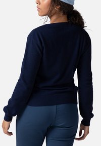 Granatowy sweter z przędzy z okrągłym dekoltem, prążkowanymi mankietami i dołem. Miękka faktura, dopasowany fason i minimalistyczny design bez wzorów.