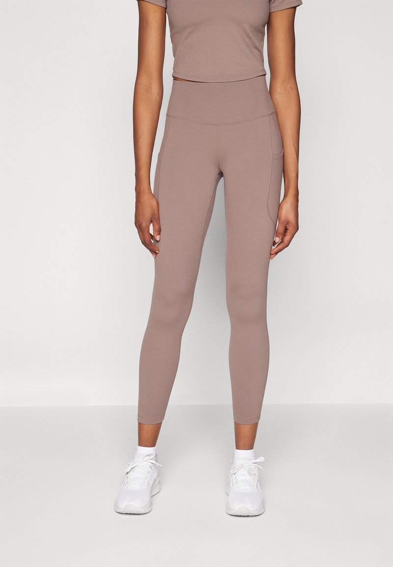 Light brown active leggings with a high waist and side pockets, paired with a matching cropped top. Smooth texture, stretchy fabric.
